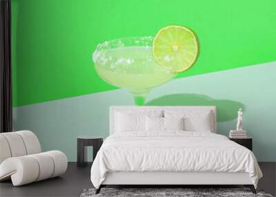 Minimal  composition with cocktail glass and fresh sliced lime against geometric green background. Tropical refreshment idea with copy space. Wall mural