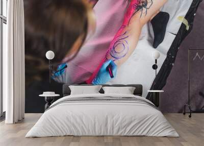 Freehand technique - tattoo master drawing with a marker on a body, high angle shot. High quality photo Wall mural