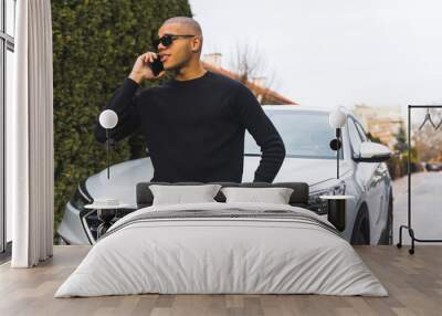 Handsome black young man on a call with his girlfriend near his luxury car on street. High quality photo Wall mural