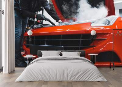 Hot steam deep cleaning of front car lid and engine area. Low angle indoor shot of a red sports car at car detailing studio. High quality photo Wall mural