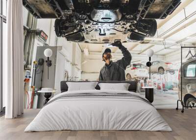 medium shot of an auto mechanic using a diagnostic tool at a car repair shop, chassis inspection. High quality photo Wall mural