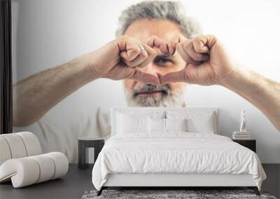 Middle-aged bearded man making heart shape with his hands close to his eyes - Isolated on white background. High quality photo Wall mural