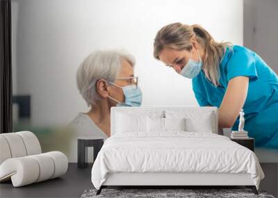 Young nurse working in a medical clinic helps out with vaccination process. Elderly people and vaccines concept. High quality photo Wall mural