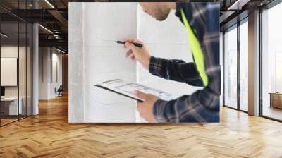 Asian inspector checking structure of new property and taking note in the clipboard for review and fix the house before sell to client Wall mural