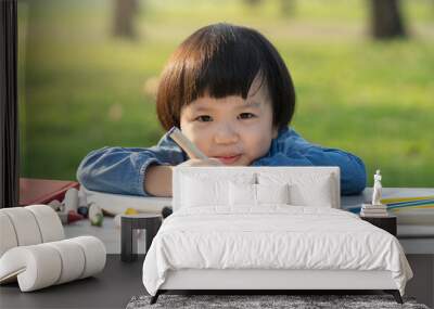 asian little girl drawing on paper in garden. Wall mural