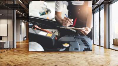 Auto check up and car service shop concept. Mechanic writing job checklist to clipboard to estimate repair quotation to client at workshop garage. Wall mural