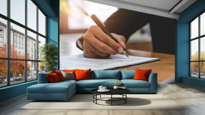 businessman sitting at desk holds pen signing contract paper, lease mortgage, employment hr or affirm partnership Wall mural