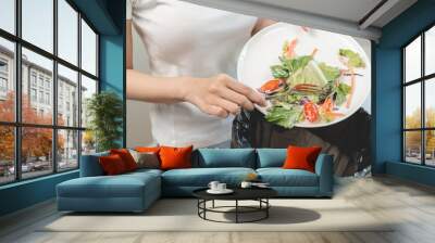 Compost from leftover food in the meal in household, female hand holding left over meal use fork scraping waste, rotten vegetable throwing away into garbage, trash or bin. Environmentally responsible Wall mural