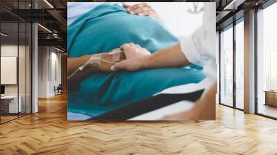 Doctor touching hands to encouragement mental of elderly patient after surgery at bed in hospital. Wall mural