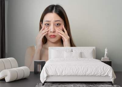 lack of sleep problem, Worried Asian young woman pointing finger at dark circles under her eyes Wall mural