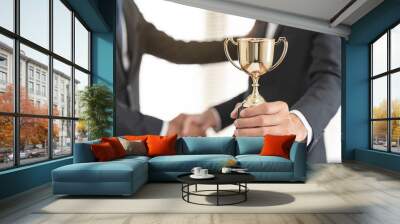 The hands of an employee receiving a golden cup reward from the company manager represent his performance in his career job reward. Wall mural