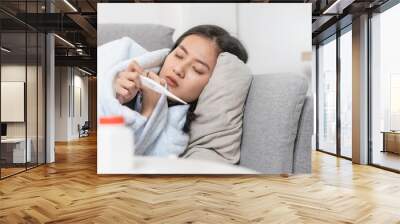 Woman measuring temperature her body on the bed. person got fever lying on the sofa. Wall mural