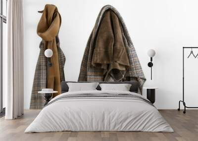 Two garments hang on a hanger, a plaid jacket and a brown scarf. The jacket is folded and the scarf is draped over the hanger. Wall mural