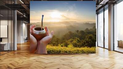 hand holding yerba mate bowl on sunrise nature background Wall mural