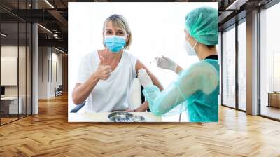 woman wearing mask getting vaccinated concept of coronavirus vaccination mask grown woman approved for covid-19 vaccination at the hospital. Female doctor immunizes against virus with medical plaster. Wall mural