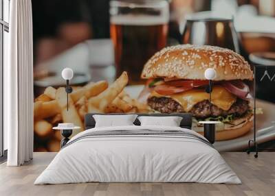 Burger and fries are on a white plate in front of a glass of beer Wall mural