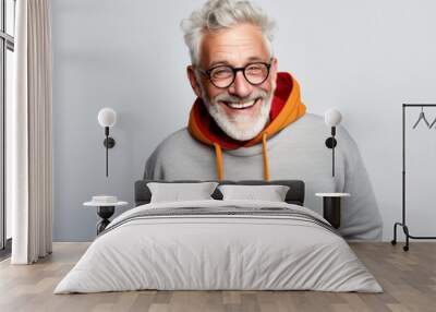 Cheerful senior man wearing glasses and casual hoodie. Active aging and style. Wall mural