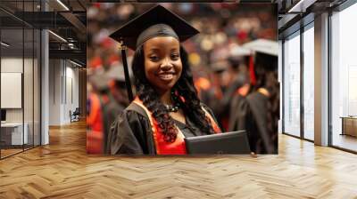 Graduate proudly holding diploma in cap and gown at graduation ceremony signifying academic achievement. Wall mural