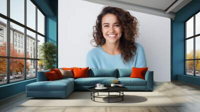 Joyful woman with curly hair wearing light blue sweater. Positive emotions and confidence. Wall mural