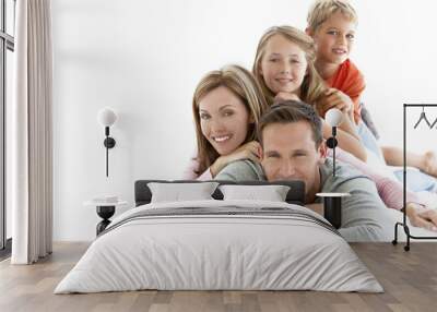 Portrait of a happy young family with two children doing a human pyramid Wall mural