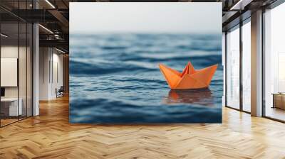 A serene scene featuring a single orange paper boat floating on calm blue water, capturing tranquility and creativity. Wall mural