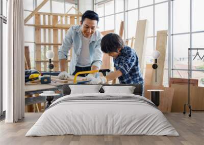 Asian father teach son using saw in woodwork. Wall mural