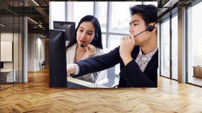 Two Asian call center operator agents working together and help each other. Concept for business, teamwork, office lifestyle. Wall mural