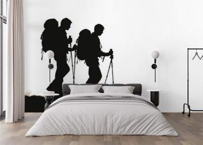 Silhouette of two hikers with backpacks walking uphill. Wall mural