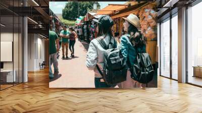 back view of two asian girls best friends travel in los angeles together on summer break. young women tourist backpacker shopping in mexico outdoor market. ladies walking in olvera street having fun. Wall mural