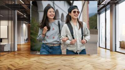 closeup portrait of two asian Taiwanese young women backpackers having fun touring around old mission santa Barbara in usa. they stand arm in arm and look into space with smiling face Wall mural