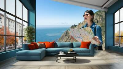 stylish asian Korean girl backpacker holding map and gazing into distance at the view of hillside sea at big sur in California usa Wall mural