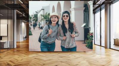 two asian girl tourist smiling walking on street shopping while travel in santa barbara america. laughing cheerful happy women on walkway wearing hat enjoy relax sunlight. attractive female lifestyle Wall mural