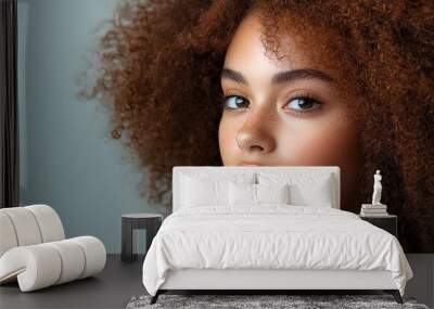 Close-up portrait of a beautiful woman with curly hair looking at the camera. Wall mural