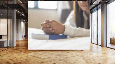 Pray and bible concept,Beautiful woman (christian) praying by hand in hand together on bible,thinking and closed her eyes.Person side view,Asian female hope for peace and read bible at bed room. Wall mural