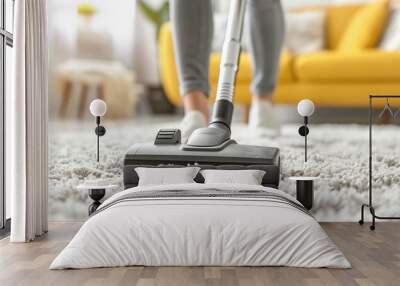 A person vacuums a carpet in a cozy living room, showcasing cleanliness and home care with a modern vacuum cleaner. Wall mural