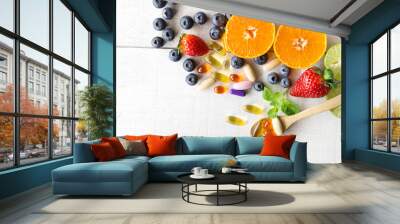 Multivitamins and supplements with fresh and healthy fruits on white wooden background. Wall mural