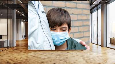 portrait of a teenage boy in a medical mask. A sickness boy with a fever in a medical mask standing in front of the house waiting for public transport with a father. Wall mural