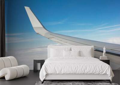 Traveling vacation abstract background. a view from airplane window showing the wing against a backdrop of blue sky and fluffy white clouds, capturing the serene atmosphere of flying. Wall mural