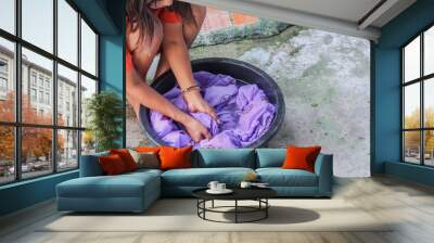 Woman wash hand dirty clothes in the basin black for cleansing Wall mural