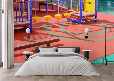 Playground climbing equipment with balance beams on colorful rubber floor in outdoors playground area at kindergarten school Wall mural