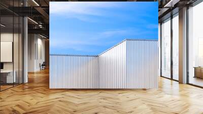 Row of aluminium corrugated metal wall of geometric industrial factory buildings against blue sky background, low angle and perspective side view Wall mural