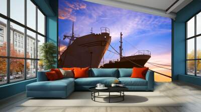 Silhouette low angle view of the old 2 nautical vessels moored at harbor against colorful sunset sky background  Wall mural