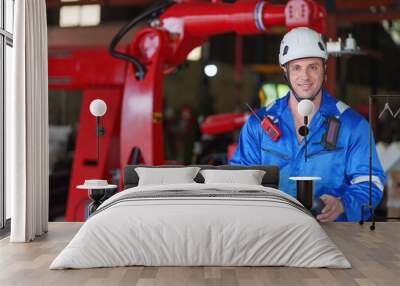 portrait young caucasian male welding robot factory engineer in protective workwear holding remote control robot arm posing to camera at automated manufacturing industry Wall mural