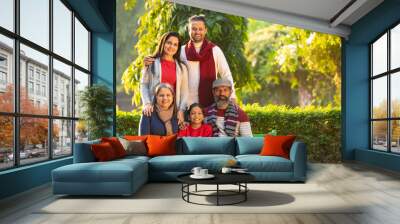 happy Indian family sitting at park in winter wear or warm clothes. Wall mural