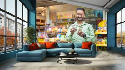 Indian man counting money at grocery shop. Wall mural