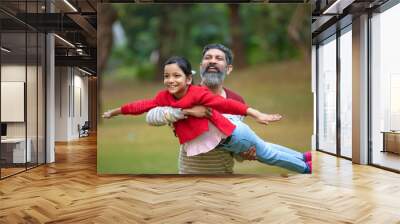 Indian man playing with his daughter at park Wall mural