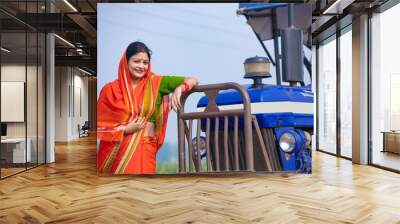 Indian rural woman standing near new tractor and giving happy expression. Wall mural