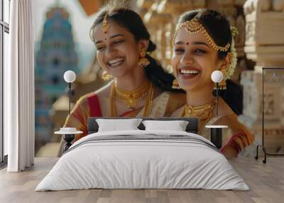 Two smiling Indian female models having fun together, wearing traditional golden jewellery Wall mural