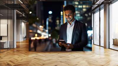 Young businessman using smartphone on city street at night. Wall mural