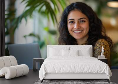 Young businesswoman looking front side and smiling while using laptop Wall mural